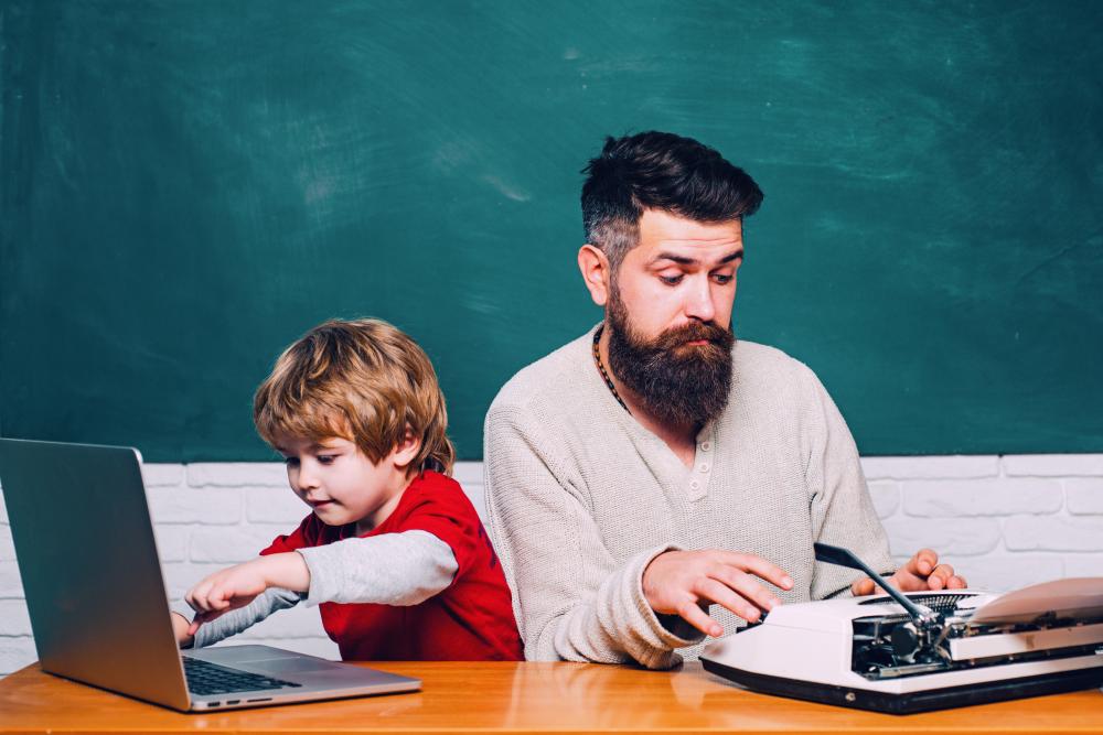 young son and hipster father working on computer and typewriter